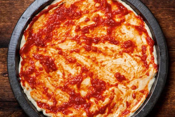 istock pizza cooking. Dough smeared with tomato sauce. 1642448465