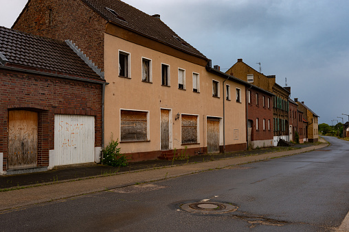 Empty street and abandoned houses with barred windows in ghost town Manheim near surface mine Hambach in North Rhine-Westfalia. The mining and energy company RWE has plans to expand the lignite mine Hambach.  For that reason the village has been evicted since 2012. Many residents now live in the new erected village Manheim-Neu.