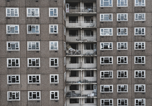 Full frame architecture background of an abandoned and derelict 1960's tower block with rows of broken windows and balconies in a downtown part of a city needing regeneration