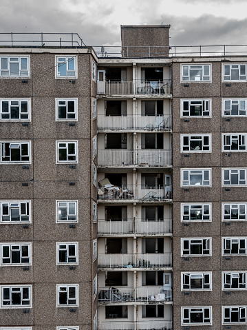 Full frame architecture background of an abandoned and derelict 1960's tower block with rows of broken windows and balconies in a downtown part of a city needing regeneration