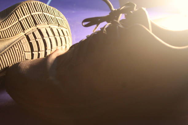 A photo of two black shoes side by side on a blue table in the light.