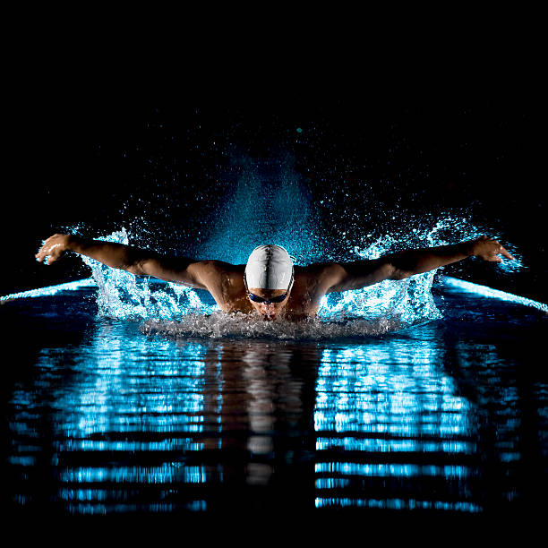 Swimmer performing butterfly stroke Taking breath swimming butterfly isolated black background professional sportsperson stock pictures, royalty-free photos & images