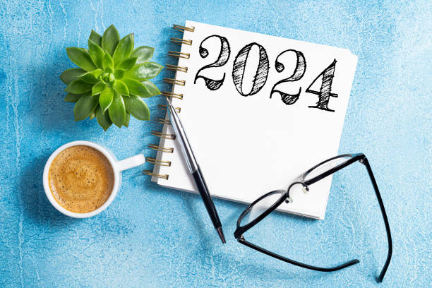 istock New year resolutions 2024 on desk. 2024 goals list with notebook, coffee cup, plant on blue table. New Year 2024 resolutions. Resolutions, plan, goals, action, checklist, idea concept 1642508610