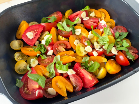 red and yello tomatoes in casserole, ready to be cooked