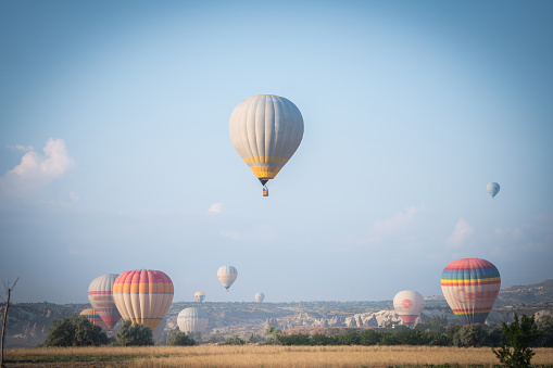 White hot air balloon flying in a blue sky with white clouds.