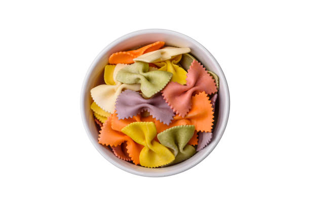 istock Raw farfalle pasta in different colors on a dark concrete background 1642543291