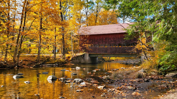 Red, wooden, covered bridge with autumn colors, Stowe, Vermont, USA stock photo