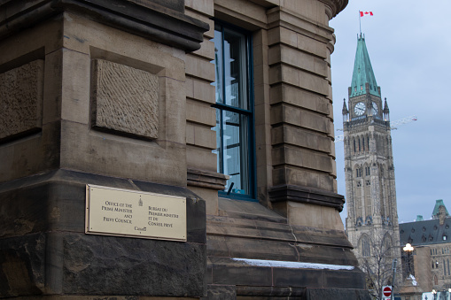 A sign for the Office of the Prime Minister and Privy Council is seen on a cloudy after in Ottawa, with the Parliament building seen in the background.