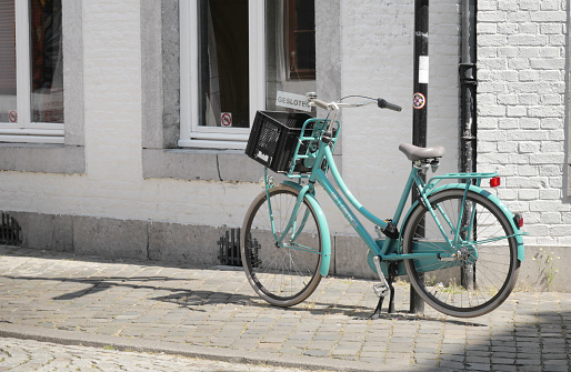 Turquoise bicycle parked in front of a townhouse in Maastricht, Limburg, Netherlands.