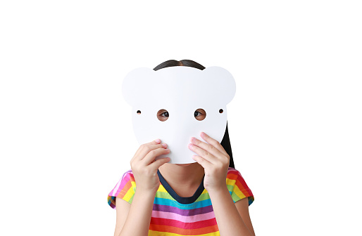 Cute little child girl holding blank white animal paper mask fronting her face isolated on white background. Idea and concept for kid dressed up playing animal face.