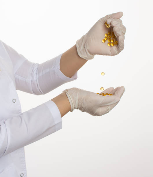 fish oil in capsules, hands in medical gloves - beautiful nurse human hand fish oil imagens e fotografias de stock