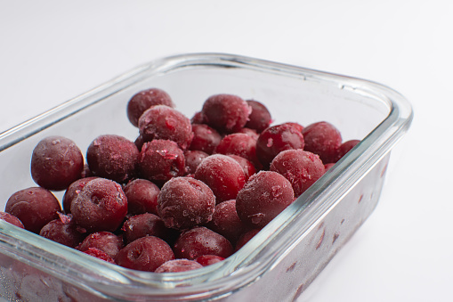 frozen cherries, juicy ripe berries in a glass bowl on a white background