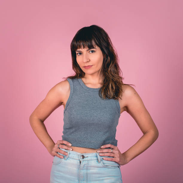 istock Studio portrait of a confidence woman with hands on hips while looking at camera over a pink background 1642601800