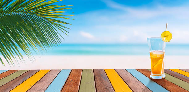 istock juice glass on multicolor wood table and tropical beach with coconut palm tree in background 1642610440