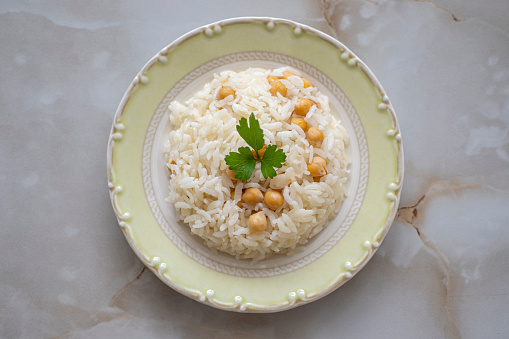 Rice with chicken and green peas on a plate over light grey slate, stone or concrete background.Top view .