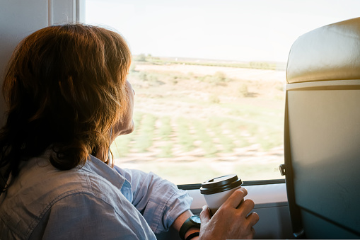 beautiful woman sitting on a train with a cup of coffee looking through the window. High quality photo