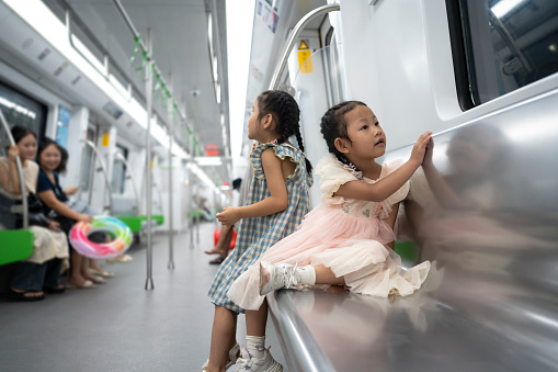 Two little Asian girls happily ride the subway