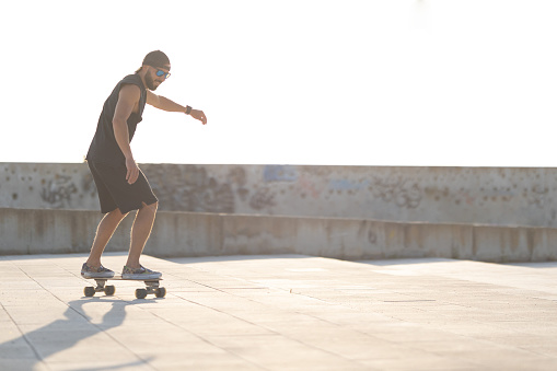 Adult attractive man skateboarding on the street. Mid shot