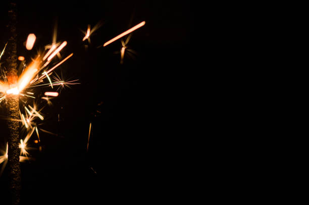istock Sparkler in yellow and orange light on a black background. 1642648080