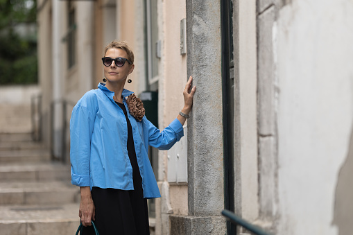 Adult stylish woman standing outdoors at european street. Mid shot