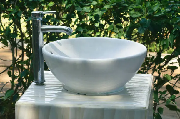 Close Up View White Ceramic Outdoor Sink beside Fence Plants In The Garden