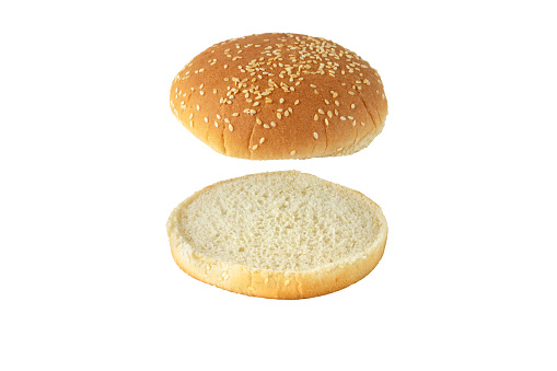 Sesame bun for burger top and bottom separated isolated on white. Round bread topped with sesame seeds cut in half.
