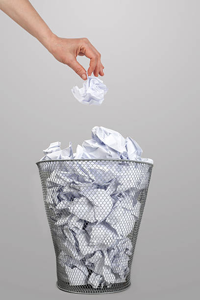 istock Woman’s hand throwing crumpled paper into a silver trash bin 164267490
