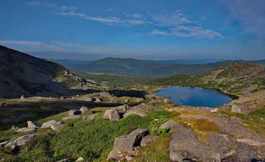 Russia. South of Siberia. Western Sayan. Panoramic view of a high-altitude lake surrounded by harsh rocks from a mountain pass in the Ergaki Natural Mountain Park.