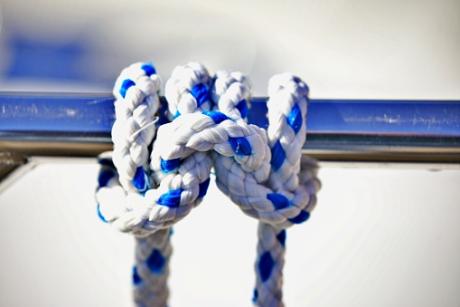 Natural colored ropes from different directions join together in a knotted ring, symbol of solidarity and cohesion, isolated on a white background, copy space