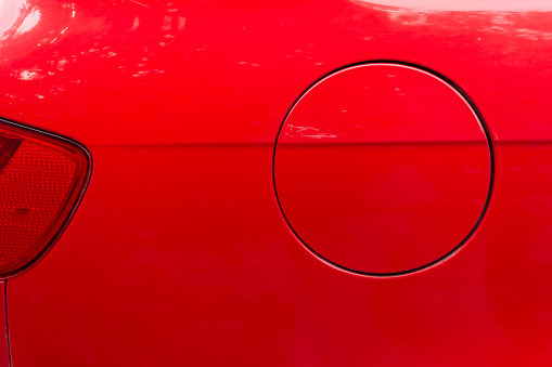 Close-up of the round fuel tank cap of a red car. Theme design and technology.