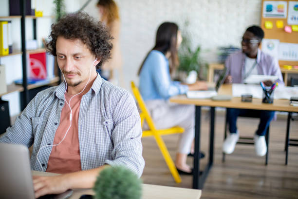 istock Businessman using laptop at modern office, her colleagues are working in the background 1642829868