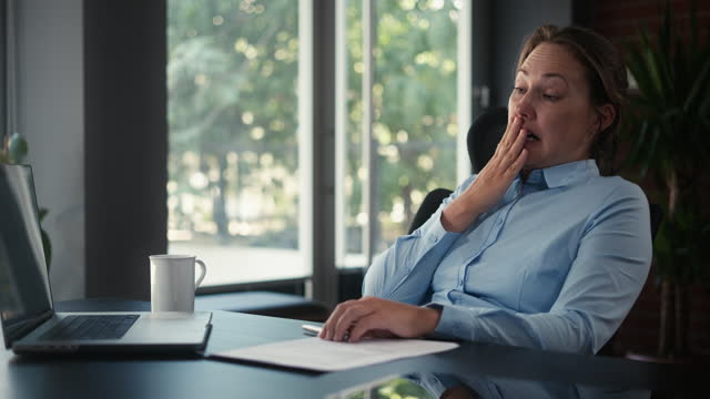 Portrait Of Sleepy Businesswoman Yawning At Workplace