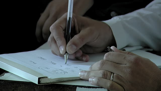 Hands of a Male Doctor Working And Making Note Information Of Patient In Notebook. Close Up.