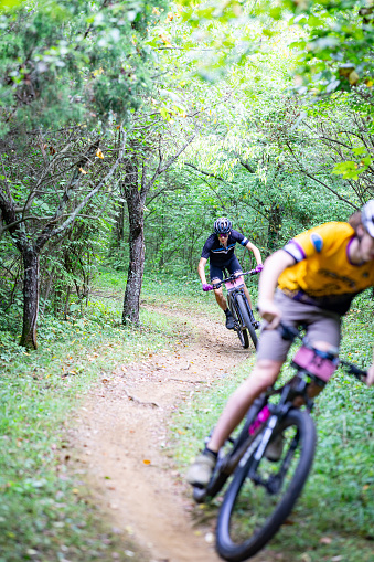 Lexington, KY - August 28 2023: Cyclists speeding on curves of Veterans park Forest on their mountain bikes