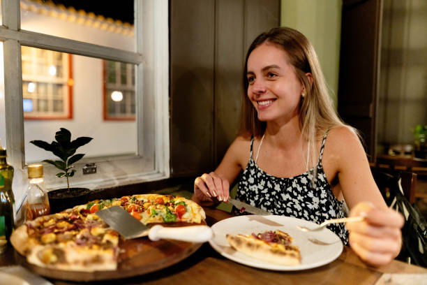 istock Attractive young woman eating pizza at a restaurant 1642950025