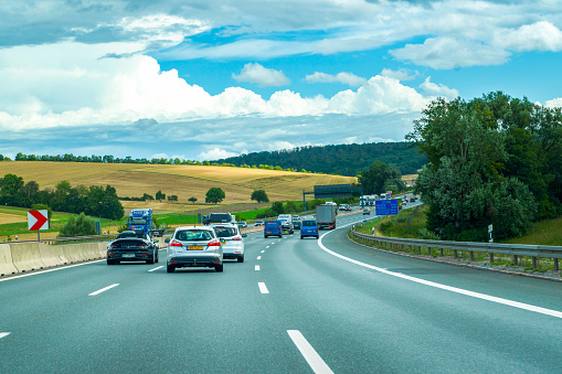 Heavy but fluid traffic on the eight-lane A10 highway in France in the direction of Bordeaux by a hot summer day with cars, vans, trailers, buses and semitrailer truck driving.