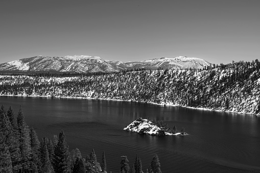 Monochrome winter image of Emerald Bay with Fannette Island in the middle and snow covered mountains in background.\n\nTaken from the Western Shore of Lake Tahoe, California, USA  looking East.