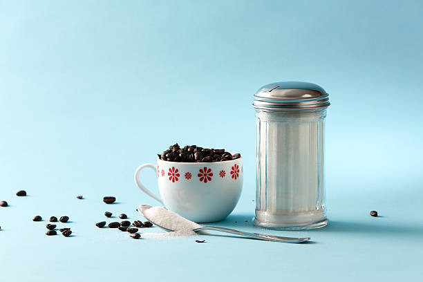 Sucre à la cuillère et une tasse de grains de café - Photo