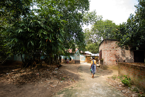 The Santali tribal hamlet at Birbhum, West Bengal, India. A woman walking towards her house at Birbhum, West Bengal