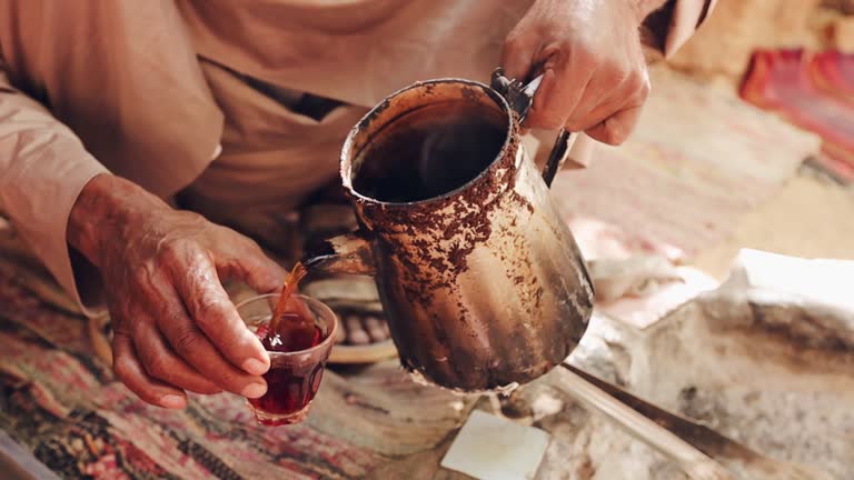 Bedouin man hands close up pouring hot tea in the cup