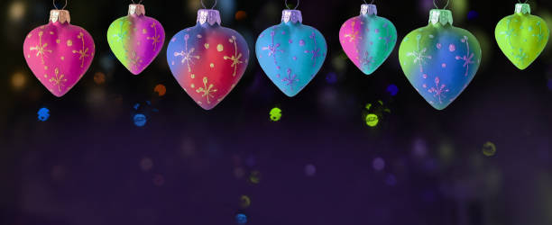 istock a row of multi-colored heart-shaped Christmas toys on a dark background with multi-colored lights and bokeh. banner. christmas new year background. 1643098357