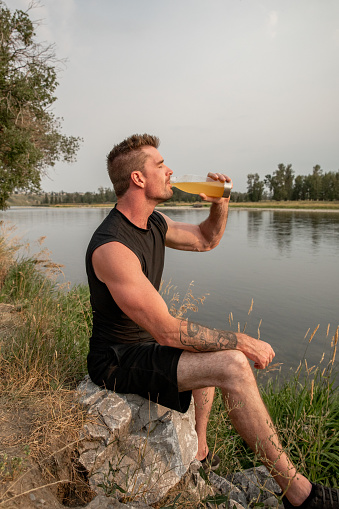 Active, healthy man running outdoors at a local city park, taking a break to hydrate.