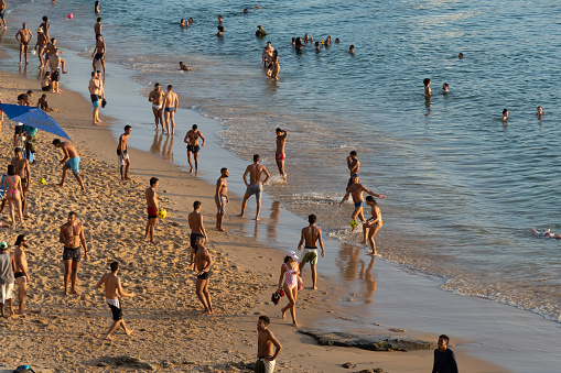 Salvador, Bahia, Brazil - August 25, 2023: People have fun sunbathing and playing beach soccer at Porto da Barra beach in the city of Salvador, Bahia.