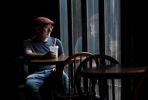 Caucasian man in a coffee shop against window
