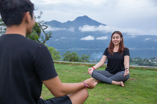 Close-up shot of two friends meditating together in the backyard with a mountain view  background