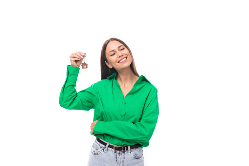 joyful young brown-eyed brown-haired woman with makeup in a green blouse earned her first apartment.