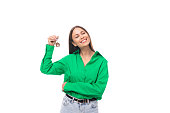 joyful young brown-eyed brown-haired woman with makeup in a green blouse earned her first apartment
