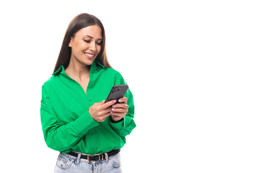 young brown-eyed brown-haired woman in a green blouse chatting on the phone.