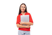 young brunette lady dressed in a red t-shirt holds a gray laptop in her hands on a white background