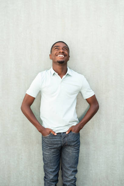 istock smiling young African American man standing by wall and looking up 1643274795